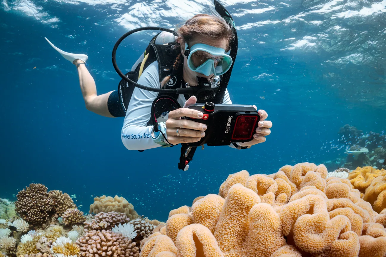 Búvár víz alatti fényképezés közben korallzátony felett – Junior Advanced Open Water Diver